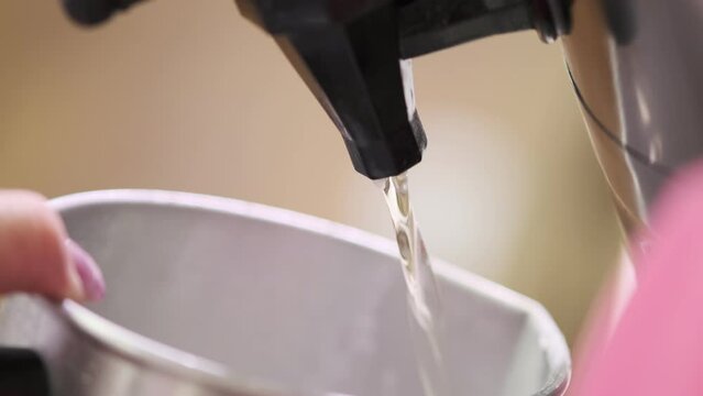 Manufacture of handmade candles. Liquid wax is poured out of the barrel. Slow motion
 