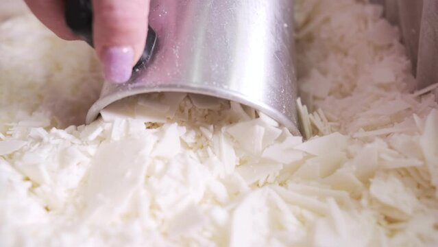 Making candles with your own hands. A woman's hand is picking up pieces of wax for candles into a metal mug. Close-up
