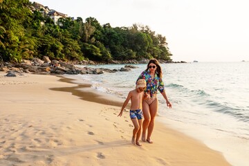 Children and adult women walking on the Nai Thon beach in Phuket 