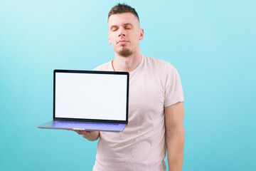 A man dreaming with closed eyes and holding a laptop with an empty blank screen on blue background. Occupation. Online. Relaxed. Shirt. Student. Wireless. Head. Dreamy. Dream. Vision. Thinking