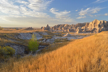 Setting sun illuminating rock formations and grasslands at Badlands NP with a dust storm in the...