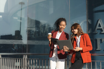 Fototapeta premium Two asia business women in conversation walking together on city street. Corporate colleagues workmate discussing new project while going to work. business outdoor.