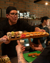 Chef handing sushi board to waiter