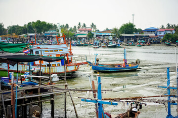 Fototapeta na wymiar Fishing boats of traditional design add pops of color to the picturesque harbor of Thailand, as they rest at the pier amidst a foreboding sky in the fisherman's valley at year 2017.