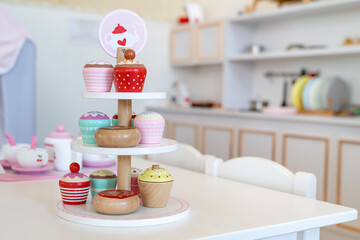 Enjoying an English afternoon tea TOY set made from wood with colorful cupcakes in a modern tower...
