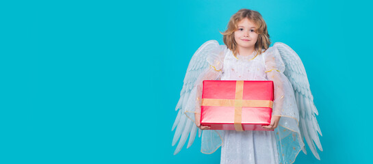 Cute child angel with gift box present. Child angel. Portrait of cute kid with angel wings isolated on studio background. Panoramic banner wide poster horizontal header.
