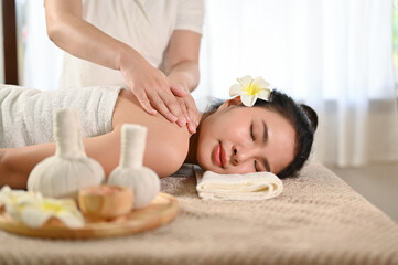 Obraz na płótnie Canvas Calm and carefree Asian woman eyes closed, lying on massage table, getting body massage
