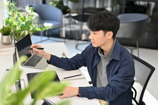 Smart Asian male programmer or web developer working at his office desk. side view