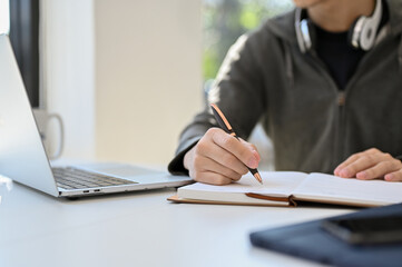 cropped image, Smart Asian male college student doing his school homework, taking notes