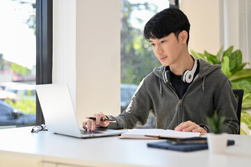 Fototapeta Smart young Asian male college student doing his school homework obraz