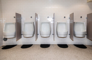 Row of  modern water conserving white porciline urinals in public restoom