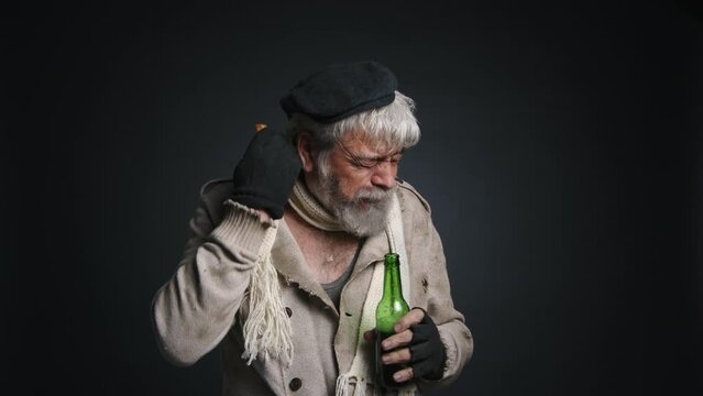 Portrait of a senior in dirty clothes drinking alcohol. Close-up shot of a homeless, caucasian man in his 70s eating bread. High quality 4k footage
