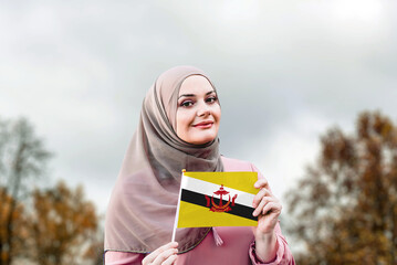 Muslim woman in hijab holds flag of Brunei