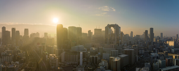 Bright sun rays through haze over downtown Osaka skyline in early morning - 559976330