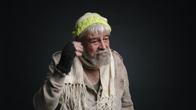 Close-up shot of a senior, homeless adult looking shocked and amazed. Portrait of caucasian man in his 70s wearing poor clothes. High quality 4k footage