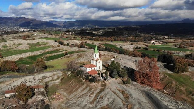 Aerial: flying towards a chappel in the catalan countryside with clouds and mountains in the background