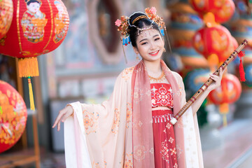 Portrait smile Cute little Asian girl wearing Chinese costumes and hold chinese flute for Chinese new year festival celebrate culture of china at Chinese shrine Public places in Thailand