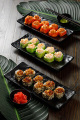 Assortment of different sushi rolls served on black plate
