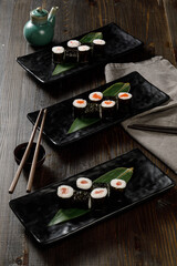 Assortment of different sushi rolls served on black plate