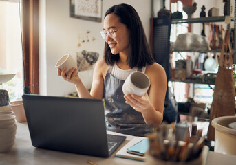 Asian woman, laptop and pottery business with smile for creative startup holding ceramic creation in the workshop. Happy woman business owner smiling for art, design or clay craft by computer at work