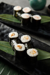 Assortment of different sushi rolls served on black plate