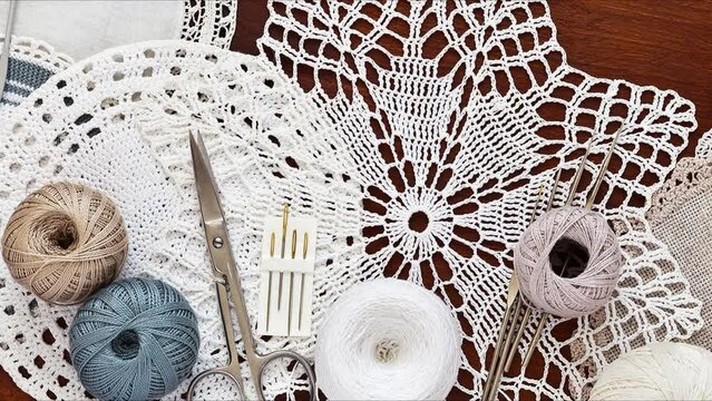 Needlework and crochet concept. Hand knitted lace doilies and crochet accessories on wooden table. Flat lay, close up, top view, mock up. Turning movement. Handmade crocheting background