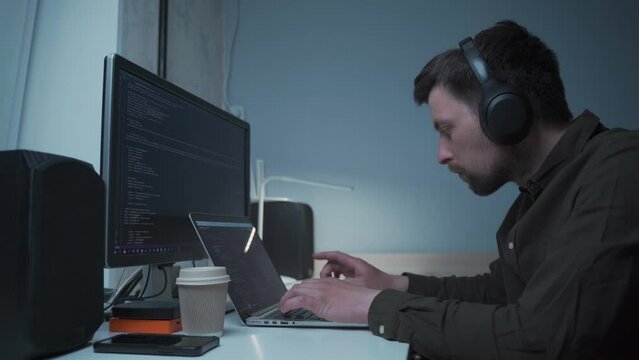 Caucasian man in headphones IT coder programmer software engineer use laptop computer typing code develop program programming java language application on screen web system app development concept.