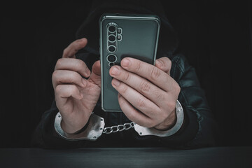 Ill-intended fraudster uses mobile. Fraudster calls. . Hacker hijacks by phone. Cellphone account fraud. Scam. handcuffs on the hands of a telephone fraudster. arrest of a bandit - obrazy, fototapety, plakaty