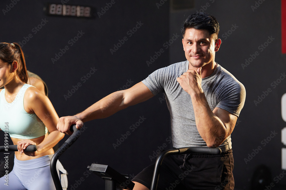Wall mural young athletic man cycling exercise bikes at the gym - Wall murals