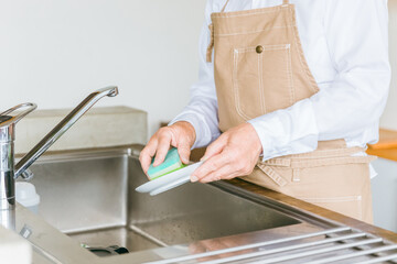 お皿洗い・食器洗いをするアジア人の高齢者男性
