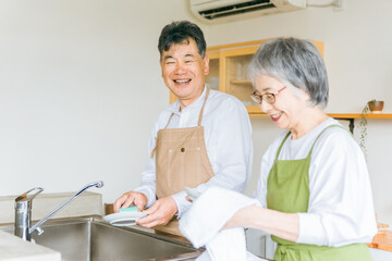 お皿洗い・食器洗いの家事をするアジア人の高齢者夫婦  © buritora