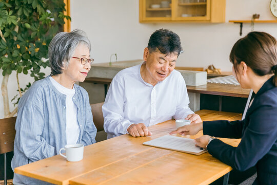 資産運用・相続税・保険・遺言書の契約書にサインする高齢者夫婦とスーツ姿のアジア人ビジネスウーマン
