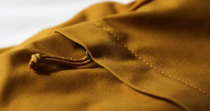 Steady shot of a zipper on a bright yellow canvas bag with lots of texture and dynamic shadows