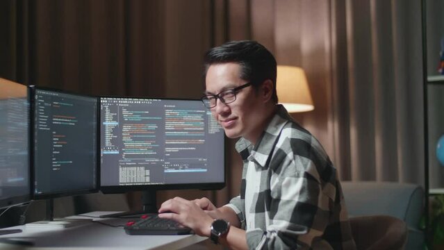 Asian Male Programmer Smiling To Camera While Creating Software Engineer Developing App, Program, Video Game On Desktop Computer At Home. Terminal With Coding Language 
