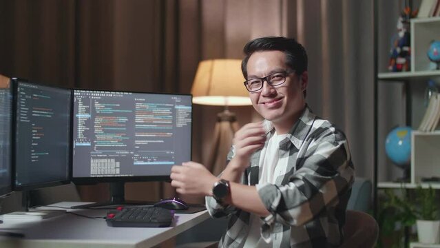 Asian Male Programmer Smiling And Crossing His Arms While Creating Software Engineer Developing App, Program, Video Game On Desktop Computer At Home

