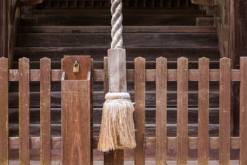 Large rope to ring bell at Japanese temple and small padlock on wooden fence - 559996193