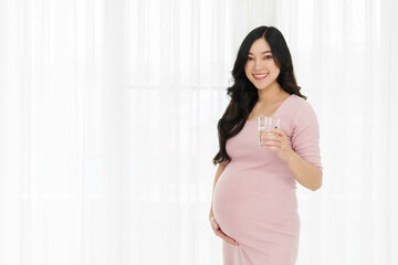 pregnant woman drinking water on window background