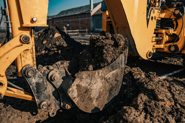 Fototapeta premium Close up of a backhoe bucket digging soil on site.