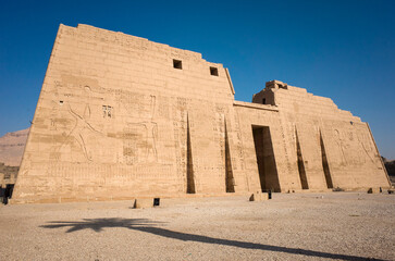 Ancient Egyptian temple Medinet Habu, dedicated to Amun, First Pylon of Mortuary Temple of Ramesses III and palm tree shadow
