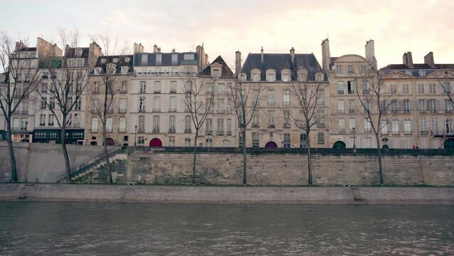 Parisian architecture with cream colors, trees without leaves for the winter season, Seine river, Paris, France. Sunset in the background