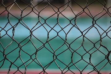 Fototapeta premium This image shows a chainlink fence surrounding a courtyard. The fence is made of metal links that are connected together to form a tall wall.