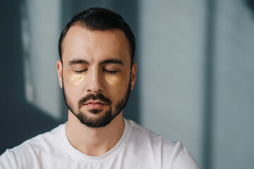 Relaxed handsome man sitting with his eyes closed and meditating while being home alone. Repose and relaxation free time, no anxiety and stress daydreaming