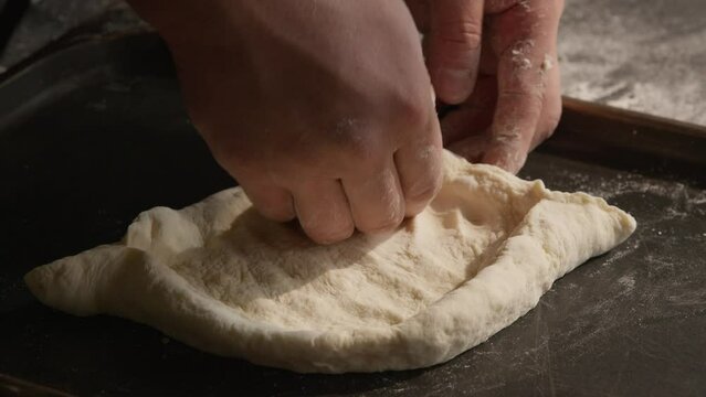 Kneading dough, making Adjaruli khachapuri boat form, closeup on hands