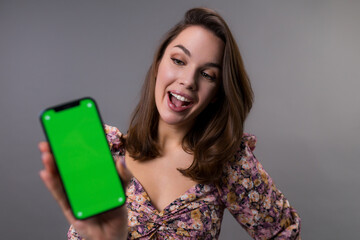 A young woman looks at the mobile phone screen with surprise. The green screen on the smartphone. Placement of ads in applications