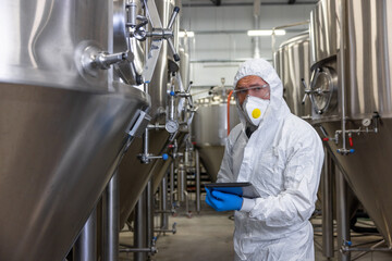 Experienced engineer overseeing the beer production equipment in a factory
