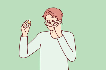 Fototapeta premium Positive man examines gold coin or piece of jewelry and lowers glasses from eyes to view rare exhibit. Guy is fond of numismatics and collecting coins from precious metals. Flat vector design 