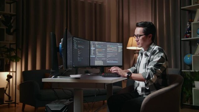Asian Male Programmer Smiling And Crossing His Arms While Creating Software Engineer Developing App, Program, Video Game On Desktop Computer At Home
