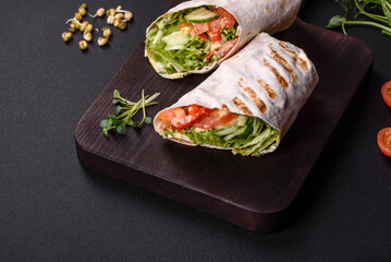 Delicious fresh shawarma with tomatoes, peppers, cucumber on a dark concrete background