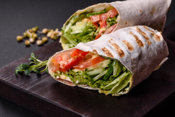 Delicious fresh shawarma with tomatoes, peppers, cucumber on a dark concrete background