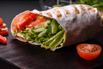 Delicious fresh shawarma with tomatoes, peppers, cucumber on a dark concrete background